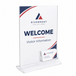 Clear acrylic welcome sign stand with a white insert displaying 'RIVERMONT SOLUTIONS WELCOME Visitor Information' and a small clear business card holder at the base, shown on a white background.